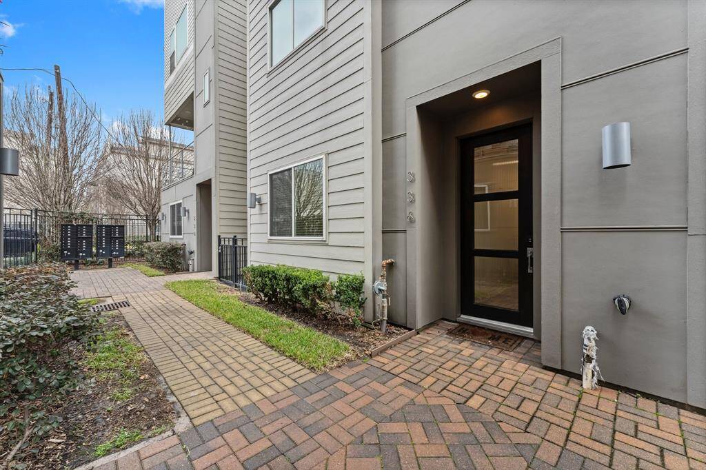 Entry features a glass-paneled front door and brick-paved path, offering a welcoming and feel.