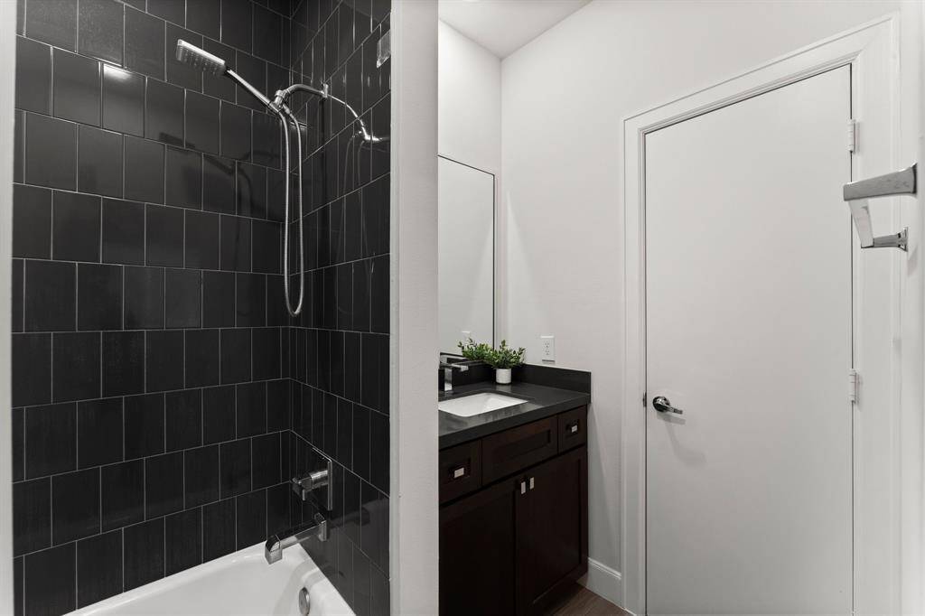 This modern bathroom features sleek black tile in the shower and a minimalist design.