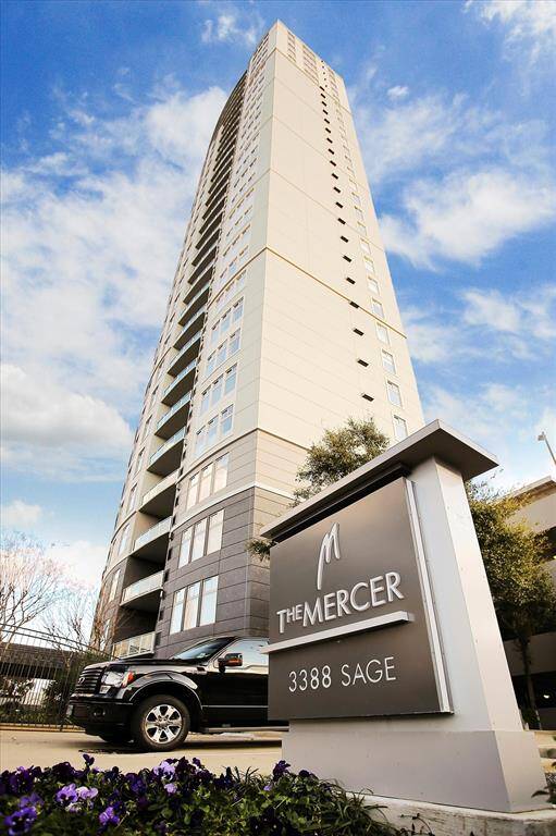 Modern high-rise building with a sleek design, located at 3388 Sage. The entrance features a well-maintained area with a prominent sign and nearby parking. Ideal for urban living with great views.
