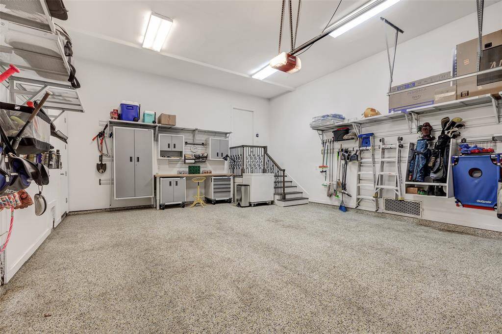 Large two car garage features epoxy floors, work bench, and custom storage/racking on all three walls