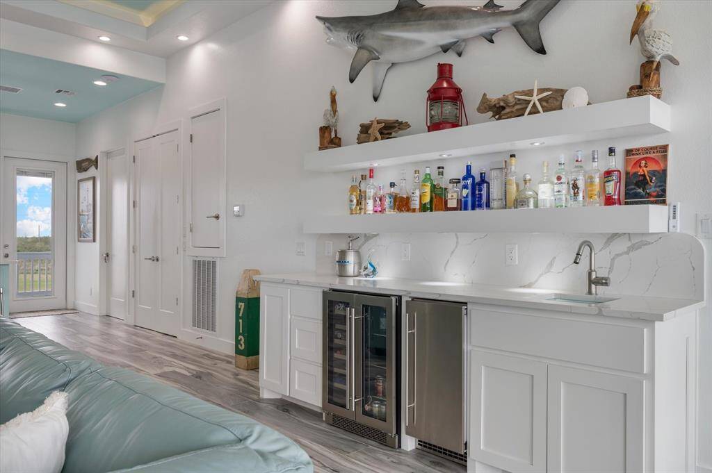 Perfect setup for entertaining! With lighted custom open shelving for glassware or bottles. Ample cabinet storage under the quartz counter. A beverage refrigerator and ice maker.