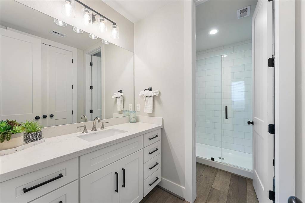 This serene bedroom offers the perfect retreat, complete with a plush upholstered bed, calming coastal decor, and natural light pouring through large windows. A space designed for relaxation and comfort.