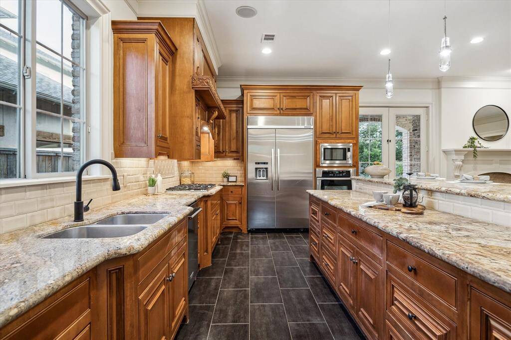 Sub Zero refrigerator, 5 burner gas cooktop, Whirlpool oven and Kitchen Aid Dishwasher.