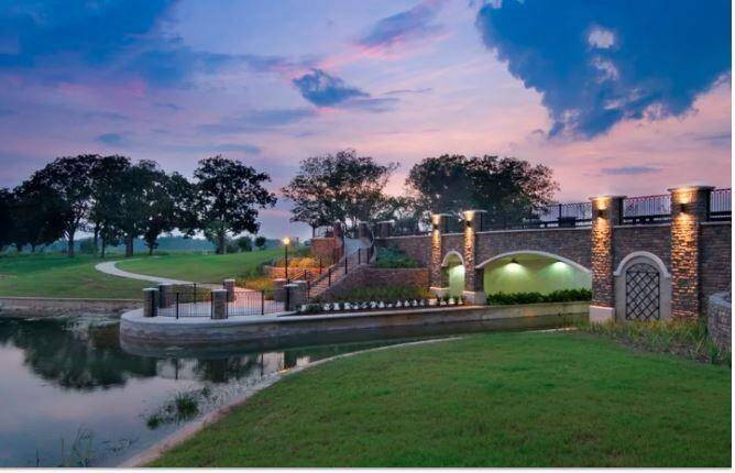 As the sun sets, the tranquil beauty of the Riverstone community comes to life. This twilight view captures the bridge, walking trails, and lake, providing a serene and calming environment for evening walks or quiet reflection.