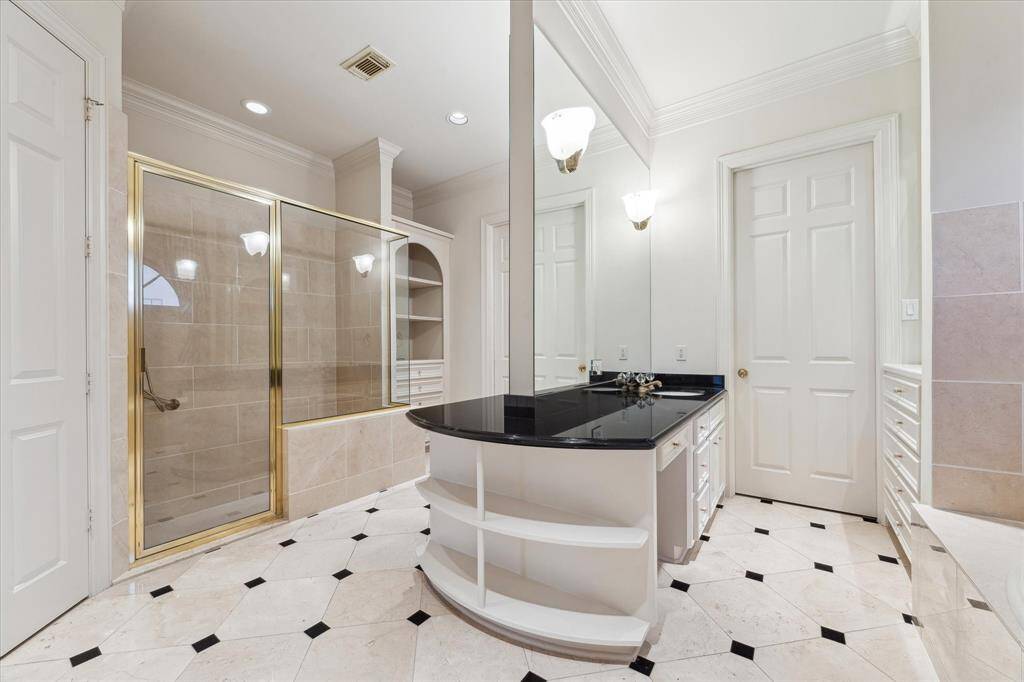 Another view of the primary bath featuring glass shower and functional builtins.  The neutral color palette, marble flooring, decorative built-ins make this bathroom luxurious.