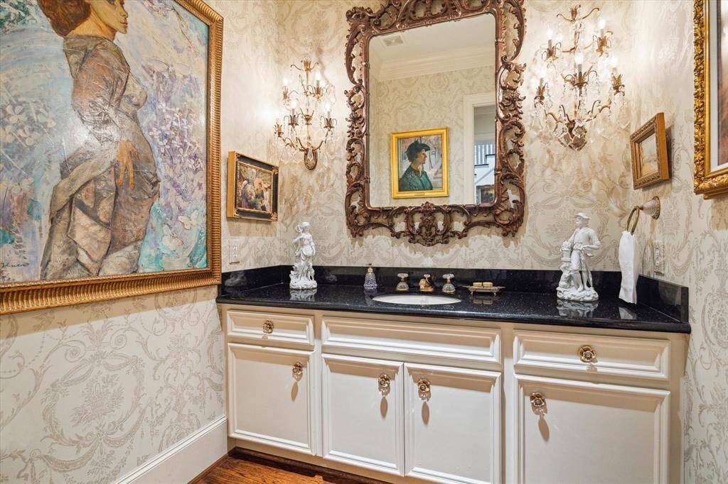 Formal powder room (one of two downstairs powder rooms) features papered walls, granite counters and decorative fixtures. Mirror is excluded.
