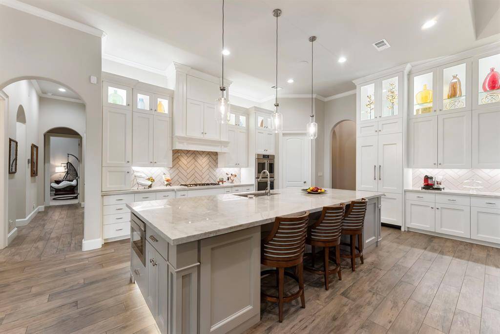 Chef’s Kitchen designed to impress—featuring Café double ovens (with French doors on the upper), a Bosch 5-burner gas cooktop, and a custom paneled built-in fridge. The massive island showcases gorgeous quartz countertops, pendant lighting, a built-in microwave, composite sink, and a convenient pop-up outlet!
