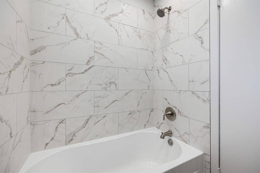 This additional view of the primary bath showcases a tub/shower combo with tile surround, perfect for soaking after a long day.