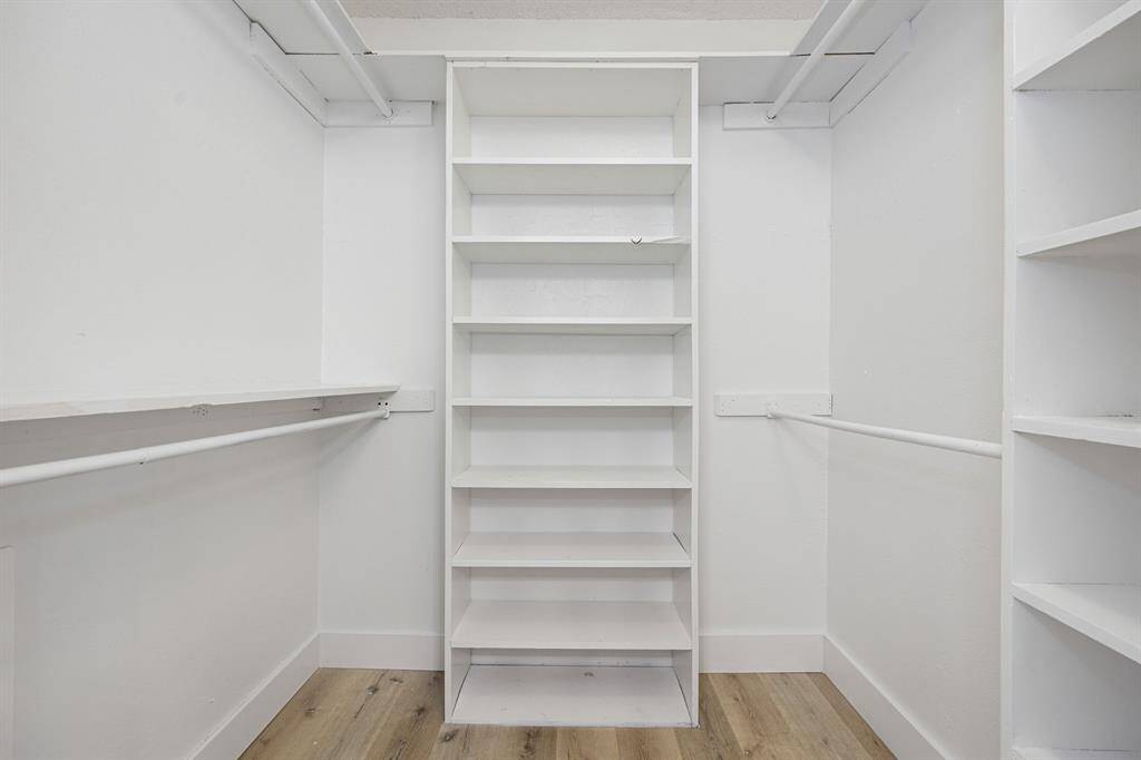 This walk-in closet offers ample storage with built-in shelving and organized space for clothing, shoes, and accessories. A perfect blend of function and style, it provides everything you need to keep your wardrobe beautifully arranged and easily accessible.