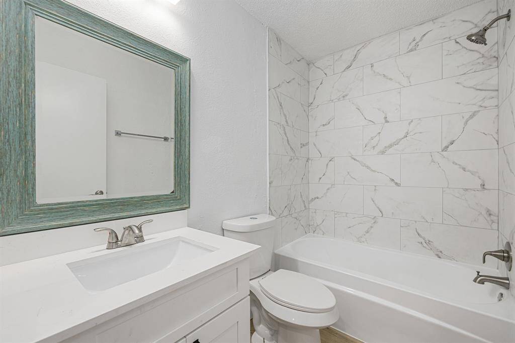 Secondary bathroom features light countertops and cabinets, neutral paint, shower/tub combo with tile surround, decorative mirror, sleek fixtures and modern finishes, plenty of space to accommodate any visiting family or guests.