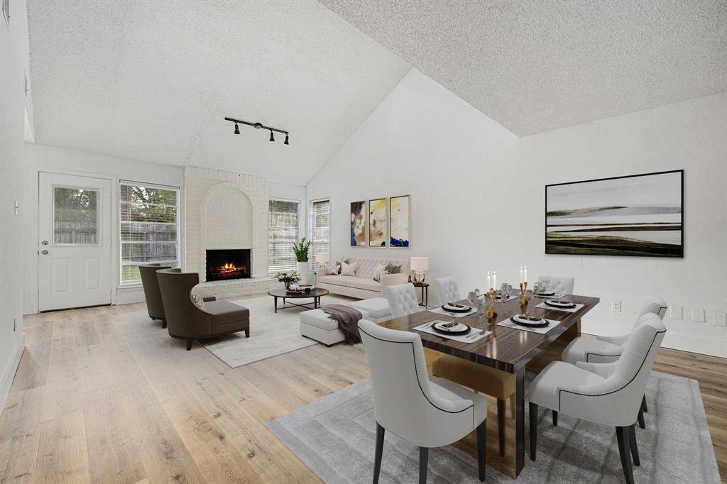 This spacious living and dining area boasts a cozy fireplace, vaulted ceilings, and large windows that fill the room with natural light. The open layout offers a seamless flow, perfect for entertaining and relaxing, with views of the inviting backyard just outside.