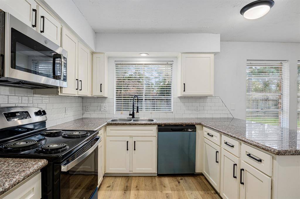 This stunning kitchen displays such a beautiful contrast with the dark granite countertops, bright cabinets, light modern backsplash, oversized breakfast bar with extra storage, custom lighting, high ceilings and walk in pantry.