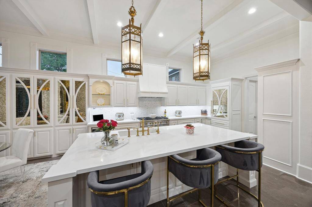 Glass cabinets, beamed ceilings, and transom windows perfect this space
