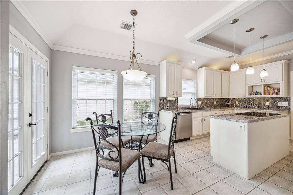 Enjoy Wednesday night lasagna or Saturday morning pancakes in this inviting breakfast area, where tile flooring, stylish lighting, and glass French doors create a bright and cheerful setting. Opening directly to an expansive patio with a built-in grill area, it’s the perfect spot for casual meals, quick bites, or lingering conversations over coffee.
