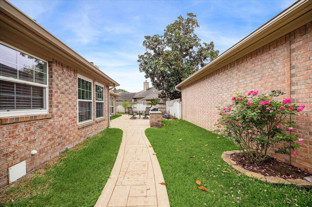 A charming sidewalk leads from the front gate to a spacious private patio retreat, complete with a built-in grill area, ideal for outdoor dining, weekend barbecues, or simply unwinding in your own backyard escape