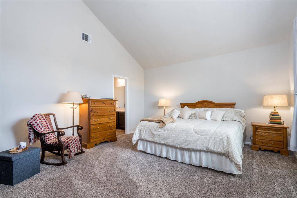 Primary bedroom w/ carpet and soaring ceilings!