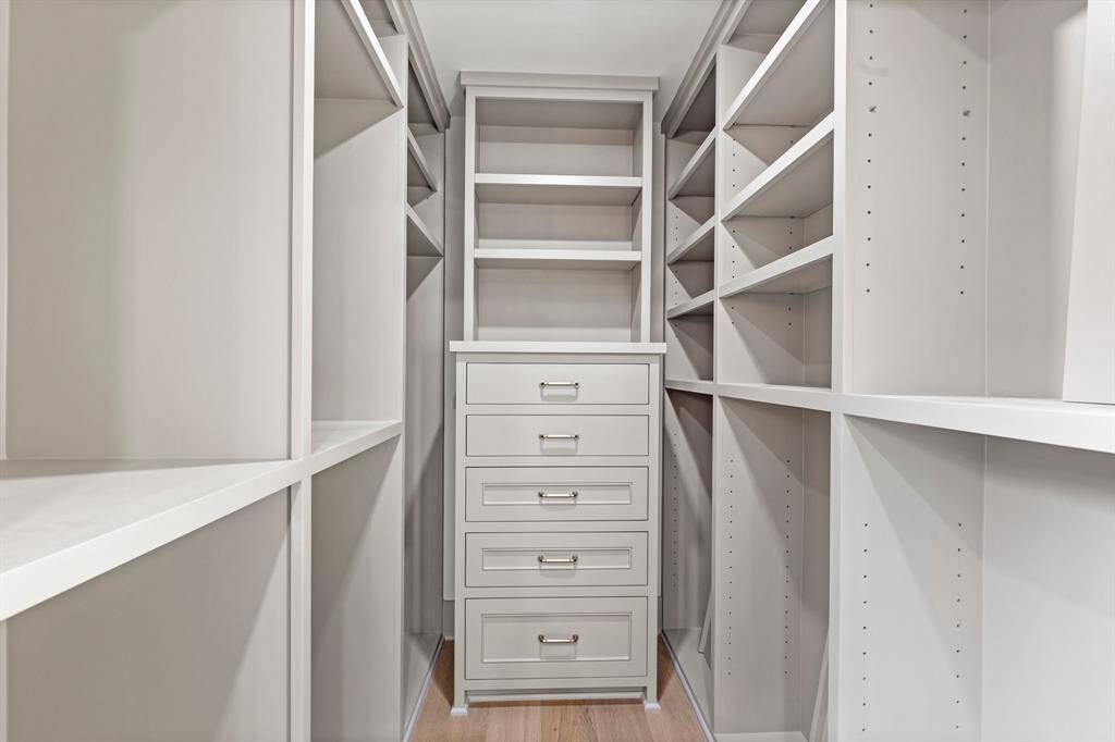 Custom wood built-ins in the walk-in closet make this space an organizers dream.