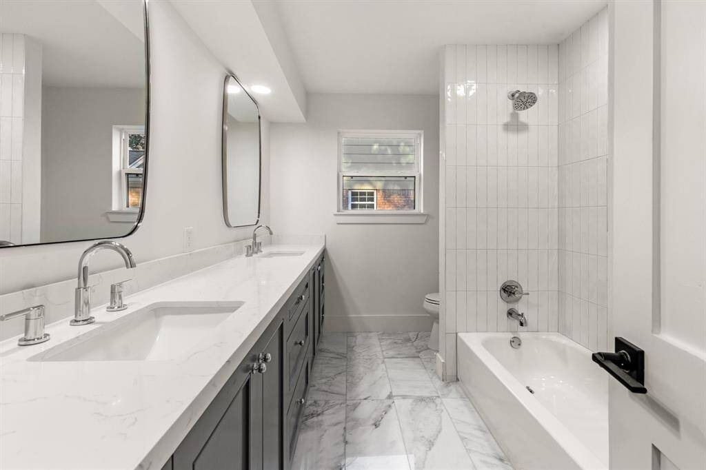 A shared guest bathroom located between the secondary bedrooms with quartz countertops, custom built cabinetry and contemporary tile.