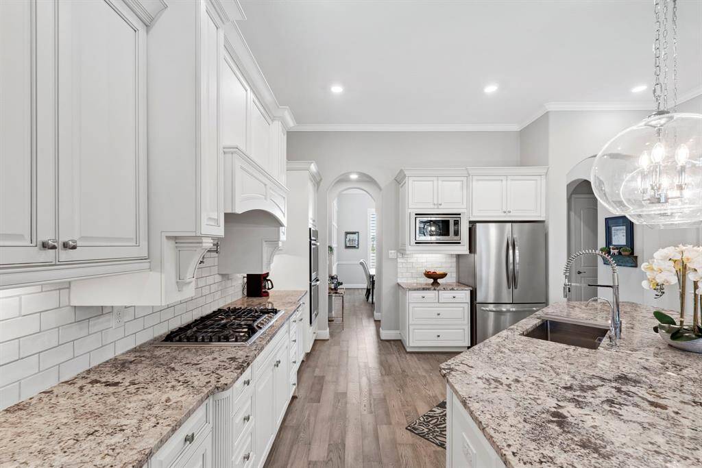 Chef's dream with gas range, pot filler and ample storage. Designed for both style and convenience, this kitchen features a 5-burner gas range with a pot filler for effortless cooking, along with abundant cabinet space and expansive countertops.