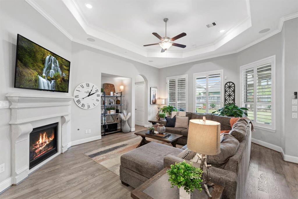 When you step into the contemporary living room featuring an elegant tray ceiling, integrated surround sound speakers, and recessed lighting that can be effortlessly controlled from your app. This space is perfect for creating the ideal ambiance whether you're relaxing at home or entertaining guests.