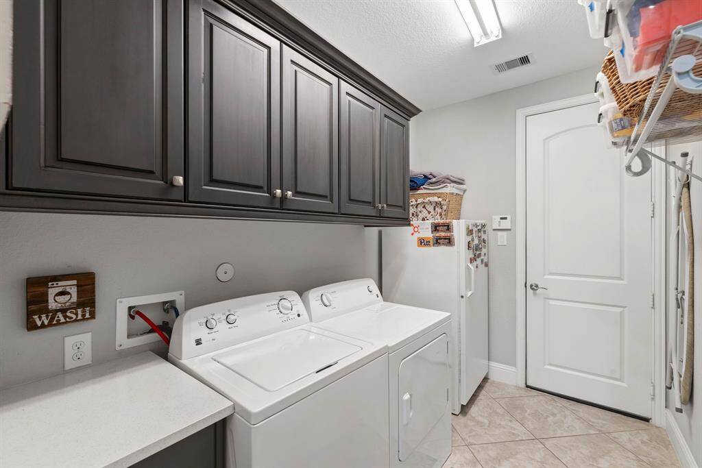Spacious utility room with ample storage. This expansive utility room offers plenty of space and abundant cabinetry for all your storage needs. Enjoy the convenience of a dryer with both electric and gas connection options.