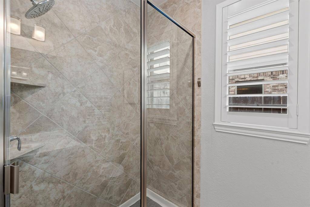 Indulge in a spa-like experience with this walk-in shower, featuring elegant floor-to-ceiling tile and built-in shelves for convenient storage.