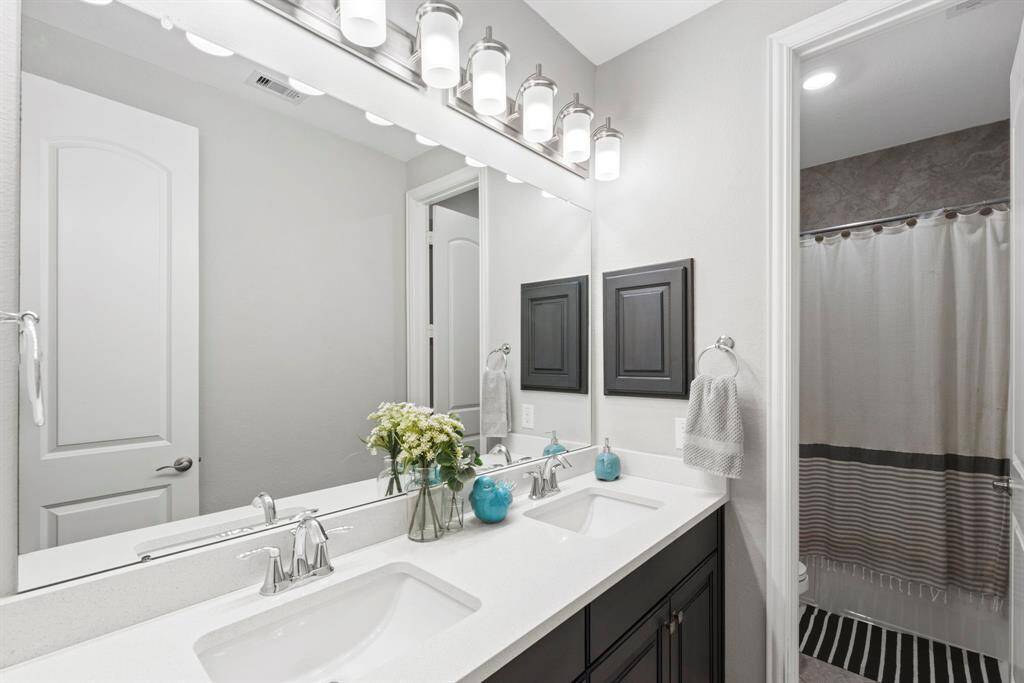 Spacious full bathroom with double sinks and elegant tile. One of the three full-size bathrooms, this well-designed space features double sinks for added convenience and a tub shower combo and beautiful tile accents.
