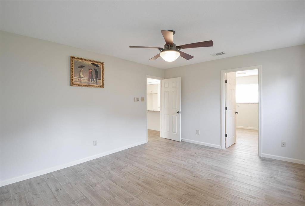 Primary Bedrrom with Ceiling Fan, Wood Plank Tile Floors.