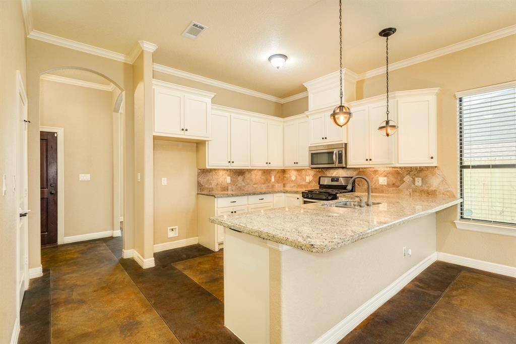 Kitchen in lined with thick granite accompanied by custom cabinets with ample storage and a large island over lookin the living room.