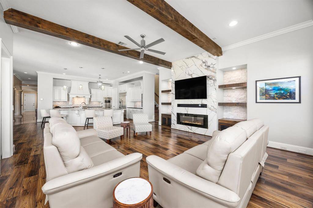 Redesigned to incorporate luxurious modern elements, timeless design & function. The porcelain slab fireplace wall truly transforms the space while the wood beamed ceiling & wood floors add warmth to the room.