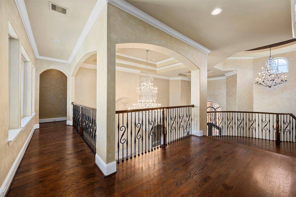 The wood balustrade & custom ironwork beautifully accent the architectural grandeur & old-world elegance found throughout this exceptional home.