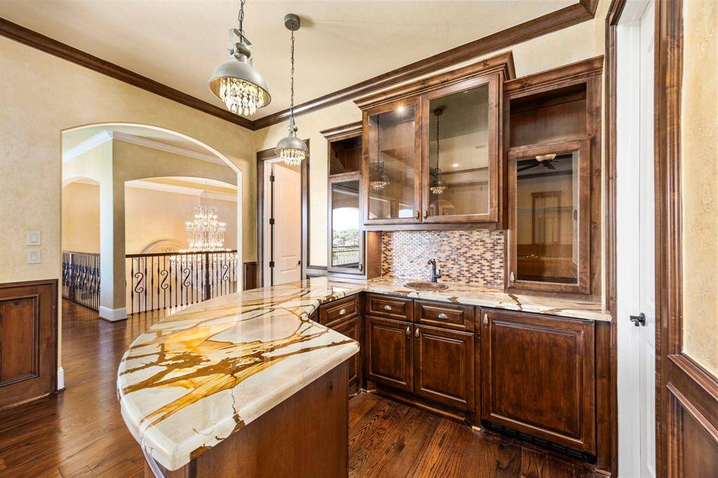 Become a mixologist for your next gathering & create a perfect cocktail for your guests. Designed with entertaining in mind, this impressive curved bar provides space for seating & is adorned with exotic granite. Bespoke lighting above illuminates the custom cabinetry & glass panel doors allow for displaying your private stock & barware.