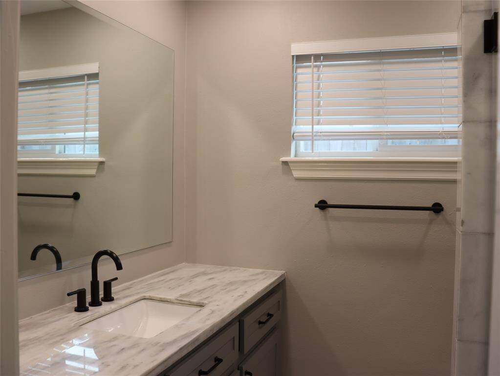 Primary bath has granite vanity, tiled shower, and marble floor