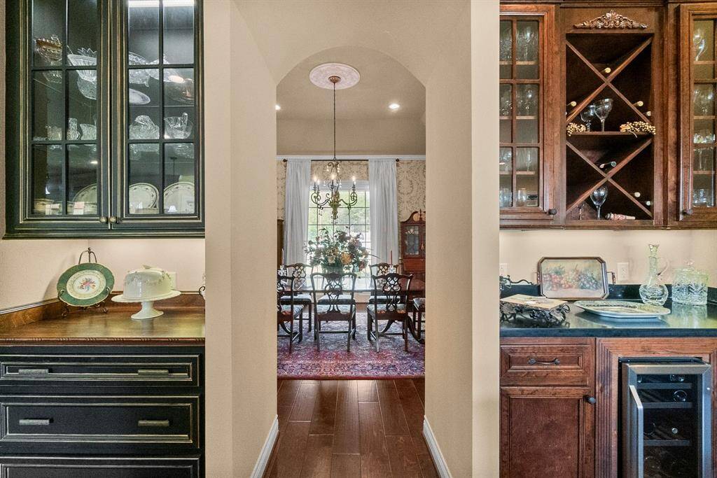 Custom cabinetry and Wine and glass storage area with wine cooler with arched entry to dining.