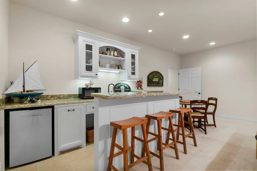 Wet bar with refrigerator, sink and bar seating in game room upstairs.