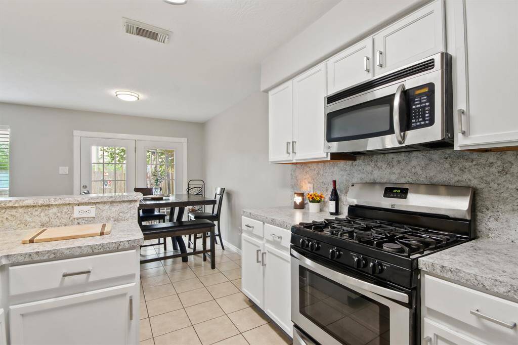 Crisp white cabinets with updated hardware provide a clean and timeless look, enhancing the sense of brightness and openness in the space.