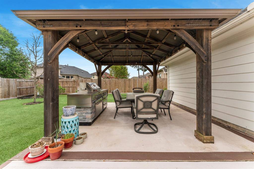 Patio is equipped with a rollable outdoor kitchen/grill and patio table with fire pit that convey with the home