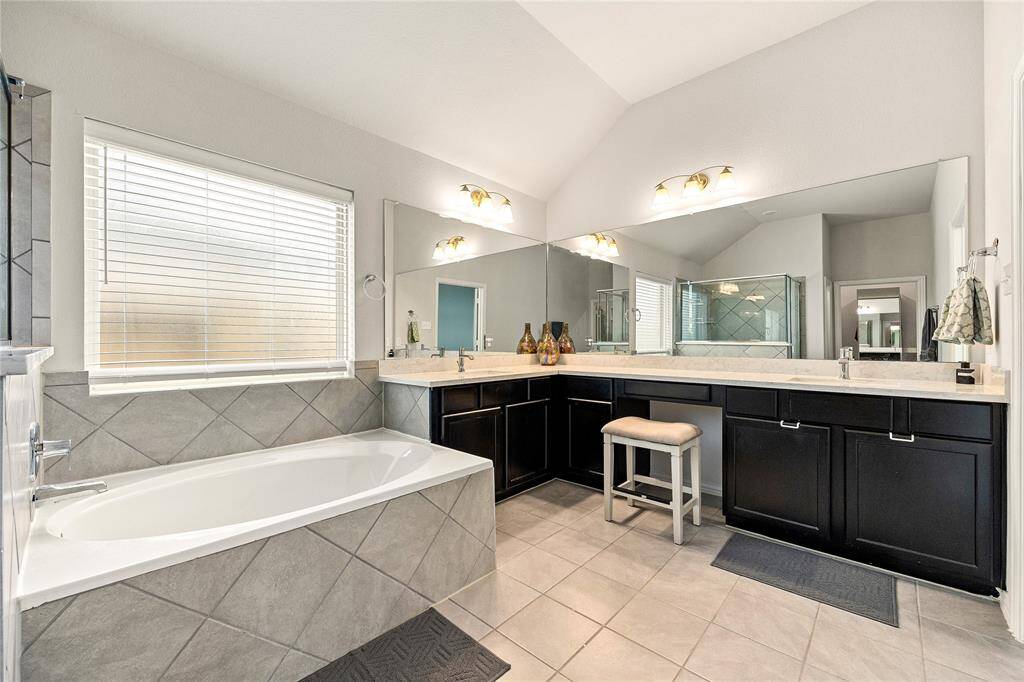 This additional view of the primary bath showcases the vanity with a large mirror and a separate garden tub perfect for soaking after a long day.