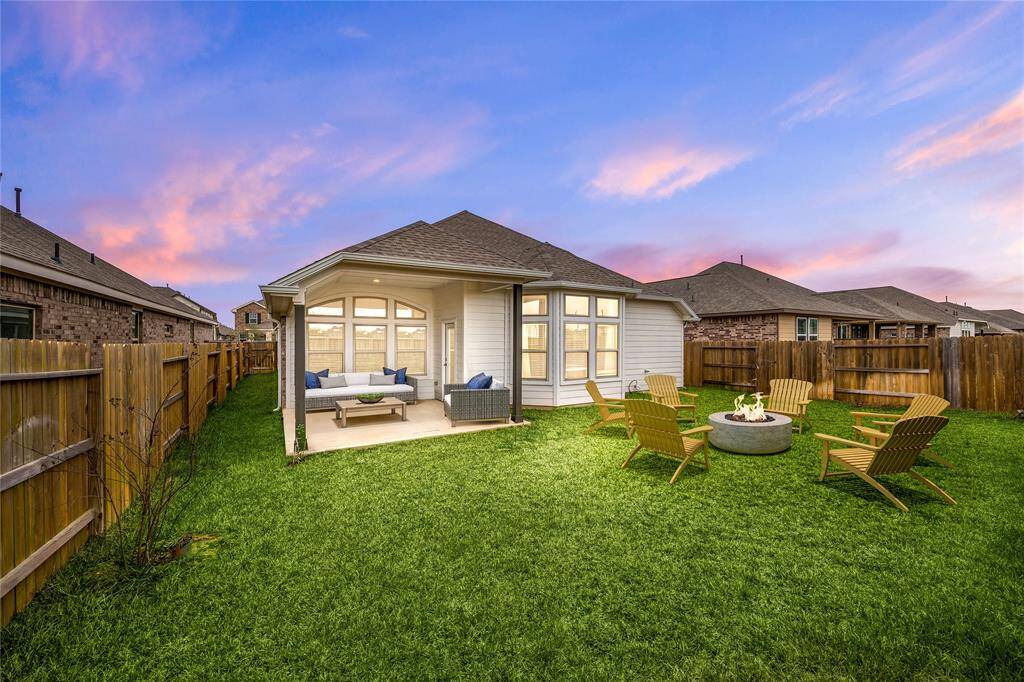 Spacious backyard with a covered patio lounge and cozy fire pit area—perfect for outdoor entertaining and relaxation. *Virtually Staged
