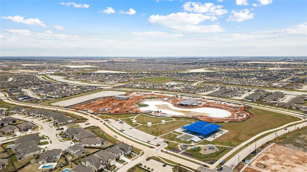 A wide aerial view of the neighborhood highlighting the future lagoon-style pool (slated for completion this summer) and surrounding residential community.