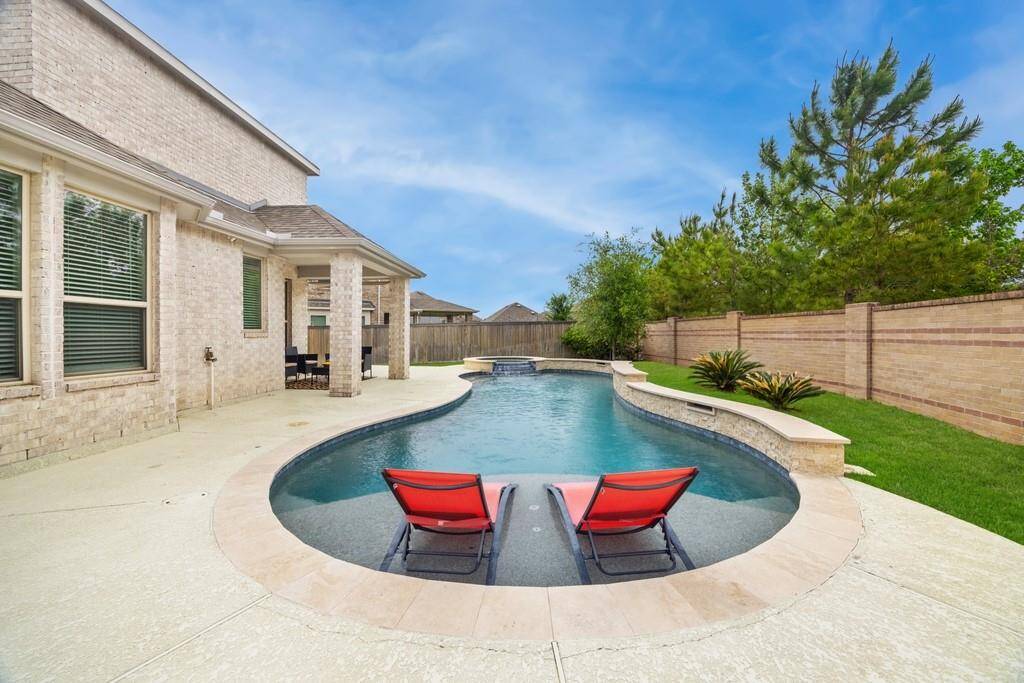 The crown jewel of this house is the magnificent outdoor living space featuring a custom pool and spa with a raised wall and beautiful water features perfect for a full day of fun  in the sun