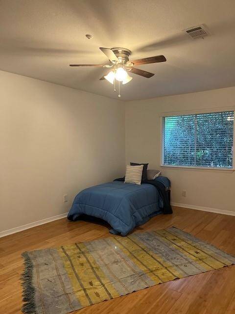 Secondary bedroom upstairs with wood flooring and ceiling fan