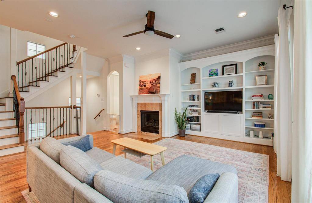 The second floor features elegant built-ins, a cozy fireplace, and access to one of two balconies—all complemented by the continued warmth of beautiful wood floors throughout.