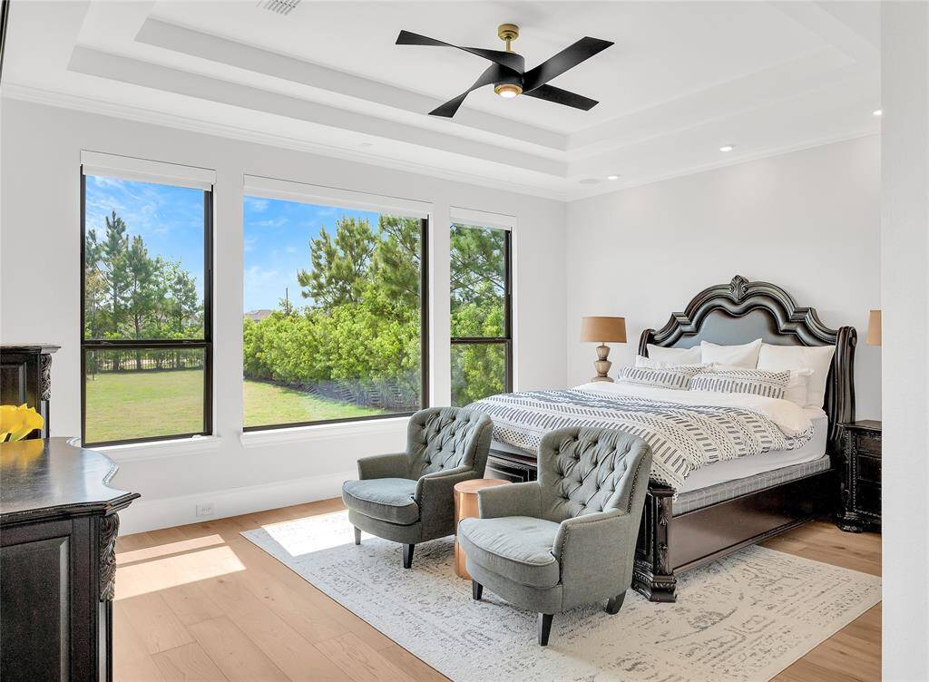 Primary bedroom suite with upgraded wood flooring and tray ceiling.