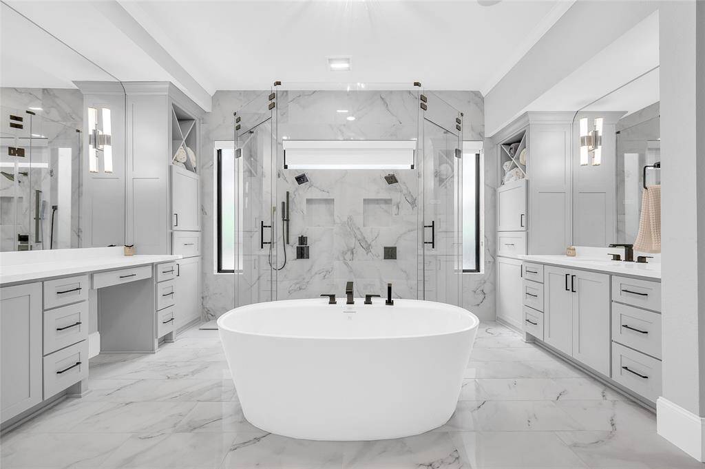 Luxurious primary ensuite bathroom with his-and-her sinks, showcasing exquisite upgraded tile and countertops.