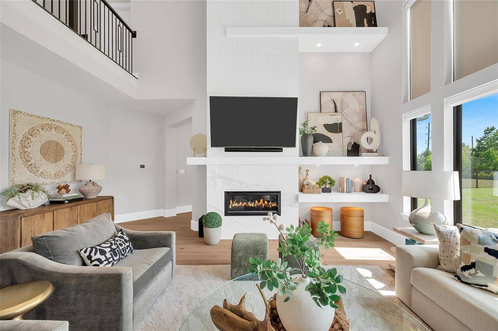 The family room boasts a sleek modern gas fireplace, custom-built shelving, and electric shades.