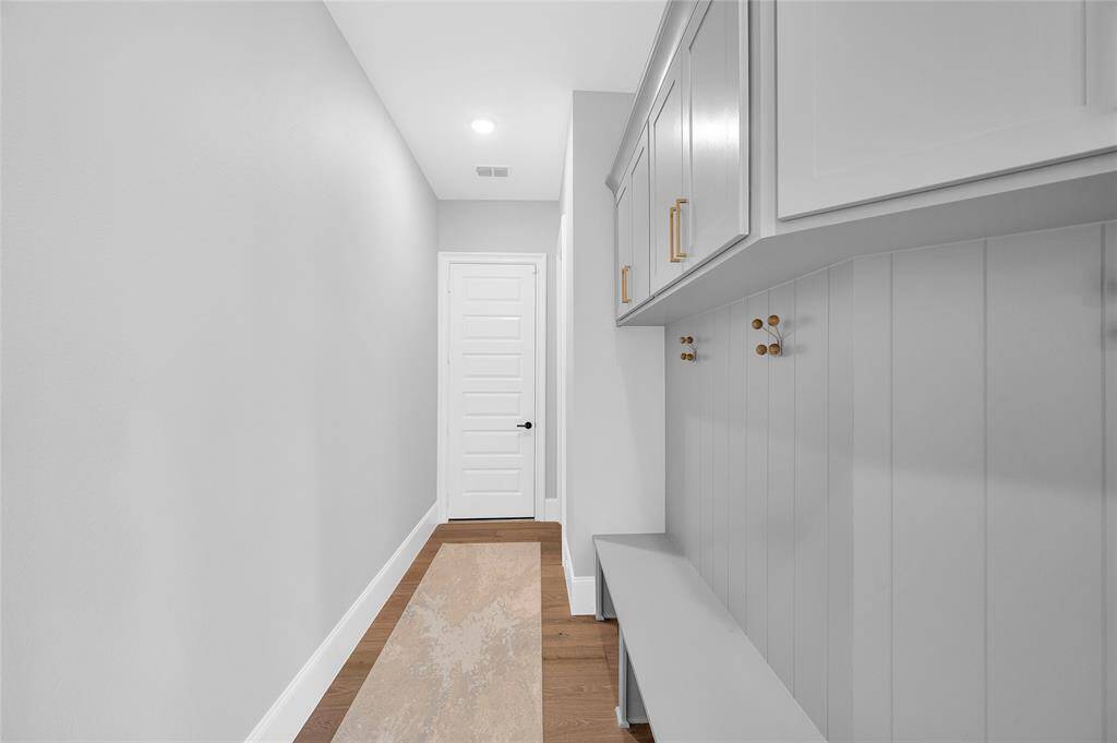 Spacious mud room with custom bench and built-ins just off the dual garage entrances and laundry room.