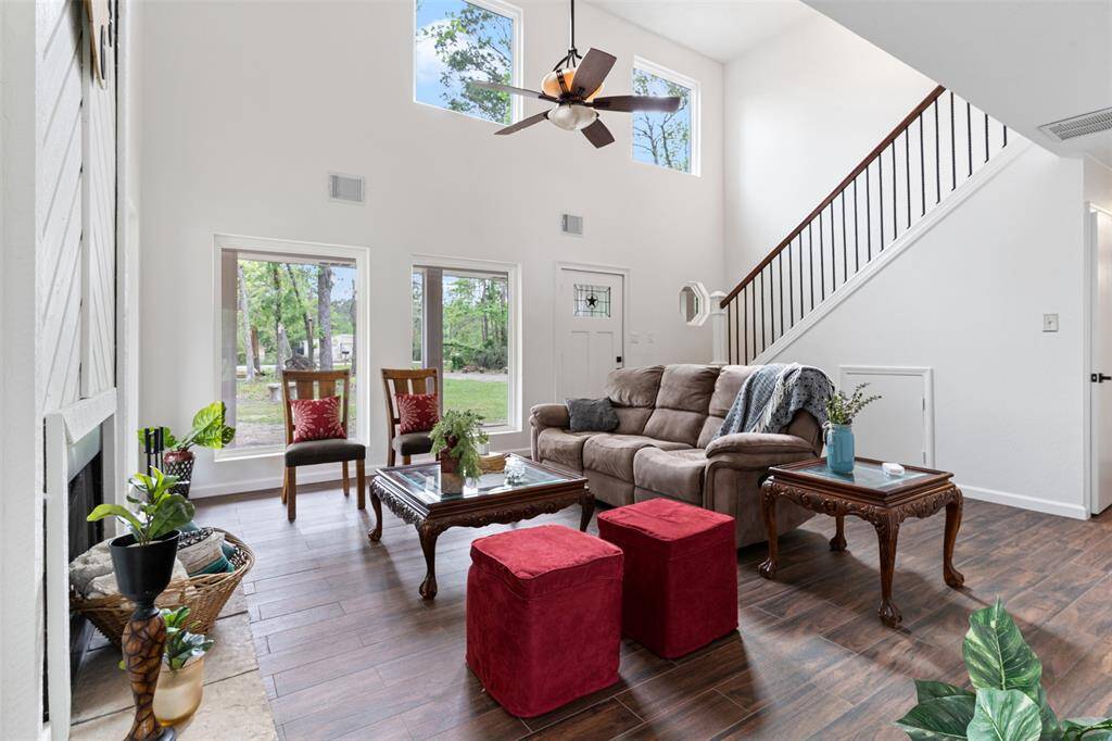 This living room features high ceilings and large windows that flood the space with natural light, complemented by new wood look tile.