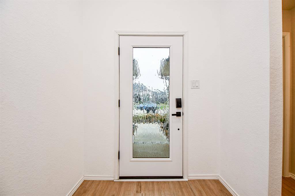 The front door makes a striking first impression with its bold, elegant design. Featuring a classic, welcoming look, the door is framed by sleek, modern hardware and a decorative glass insert that allows light to gently filter through. Its rich color complements the home’s exterior, adding to the overall curb appeal.