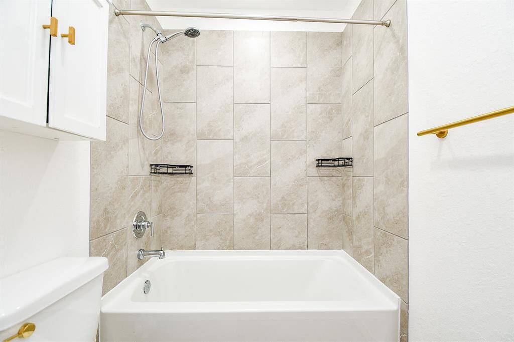 The bathtub and shower combination, accented with stylish tile work, provides a relaxing retreat for guests. Thoughtfully designed with quality fixtures, this bathroom ensures comfort and sophistication for visitors and residents alike.